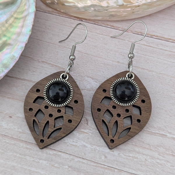 Wooden earrings with black stone centres on a wooden surface. Stainless steel hooks.