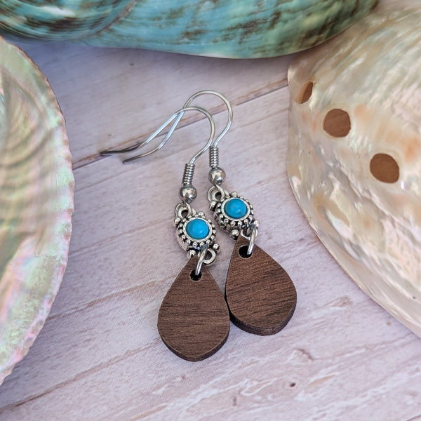 Wooden teardrop earrings with turquoise stones on a shell background. Stainless steel hooks.