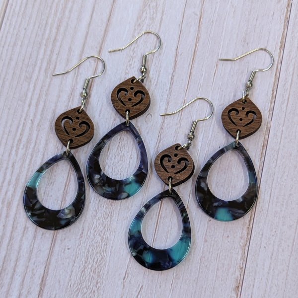 Wooden and blue resin earrings on a pale wood surface.