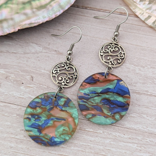 Pair of earrings with colourful circular designs on a wooden surface