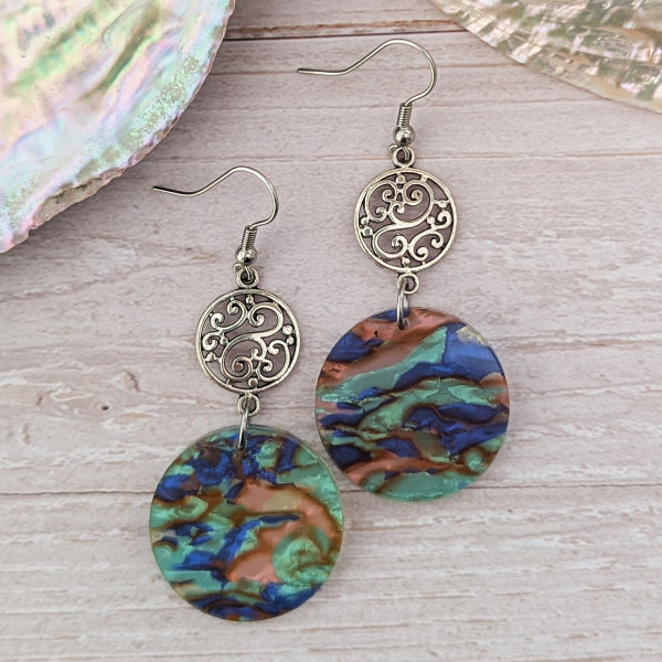 Pair of earrings with colourful circular designs on a wooden surface