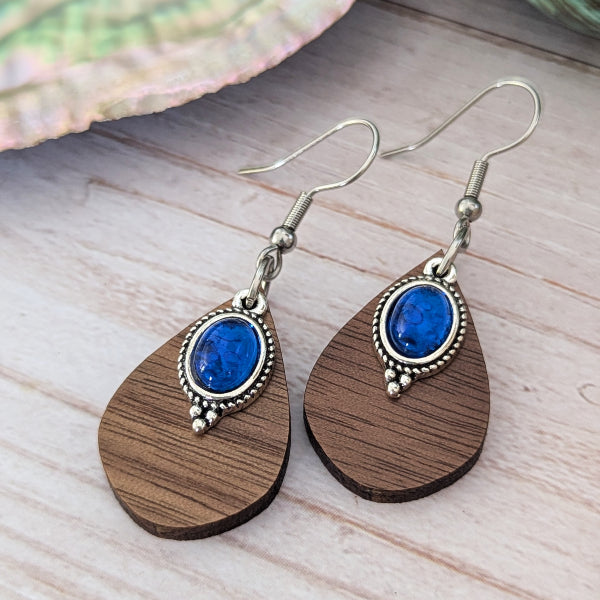 Wooden earrings with blue stones and stainless steel hooks on a wooden surface