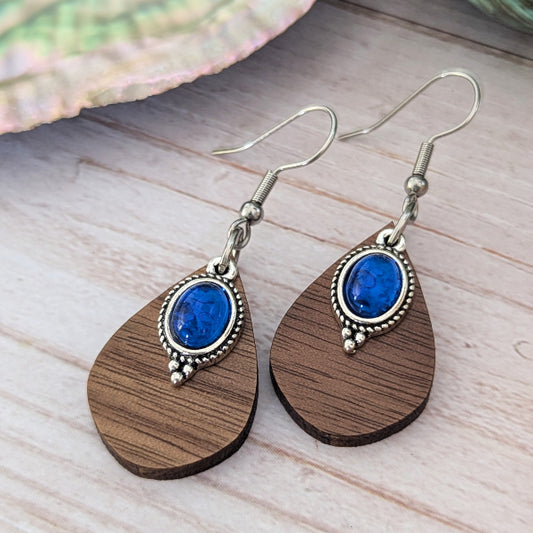 Wooden earrings with blue stones and stainless steel hooks on a wooden surface