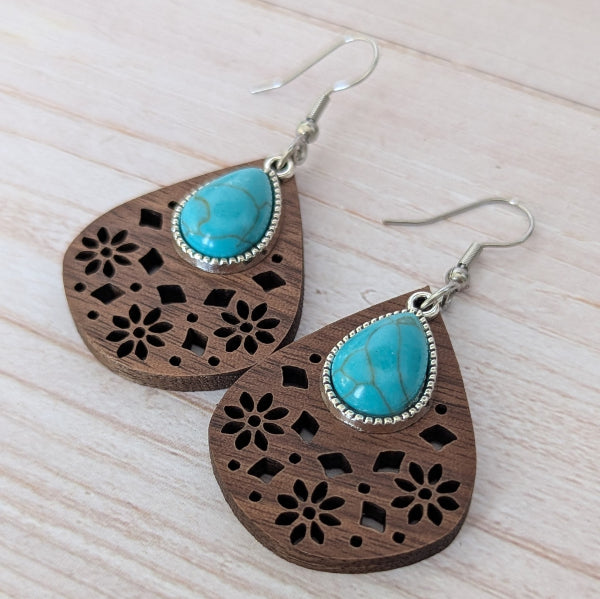 Wooden earrings with turquoise stones on a light wooden surface. Stainless steel hooks.