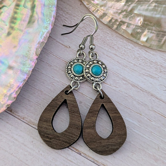 Wooden teardrop earrings with turquoise stones and silver hooks on a wooden surface. Stainless steel hooks.