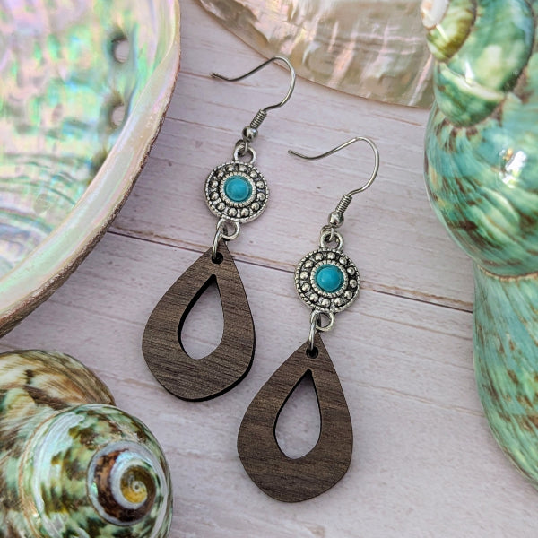 Wooden teardrop earrings with turquoise stones and silver hooks on a wooden surface. Stainless steel hooks.
