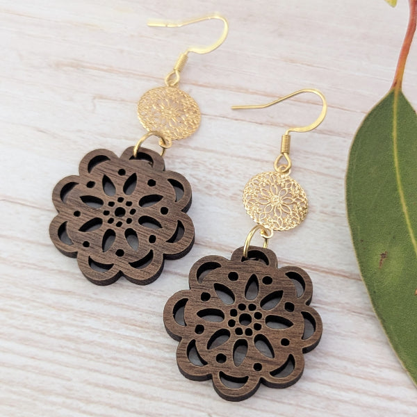 Wooden floral earrings with gold accents on a light wooden surface. Gold plated stainless steel hooks.