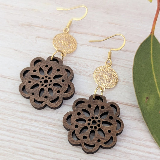 Wooden floral earrings with gold accents on a light wooden surface. Gold plated stainless steel hooks.
