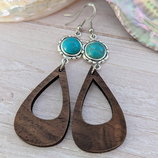 Wooden teardrop earrings with turquoise stones on a light wooden surface. Stainless steel hooks.