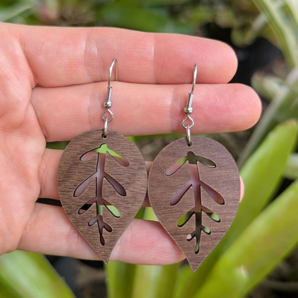 Wooden leaf-shaped earrings held in a hand with a natural background. Stainless steel hooks.