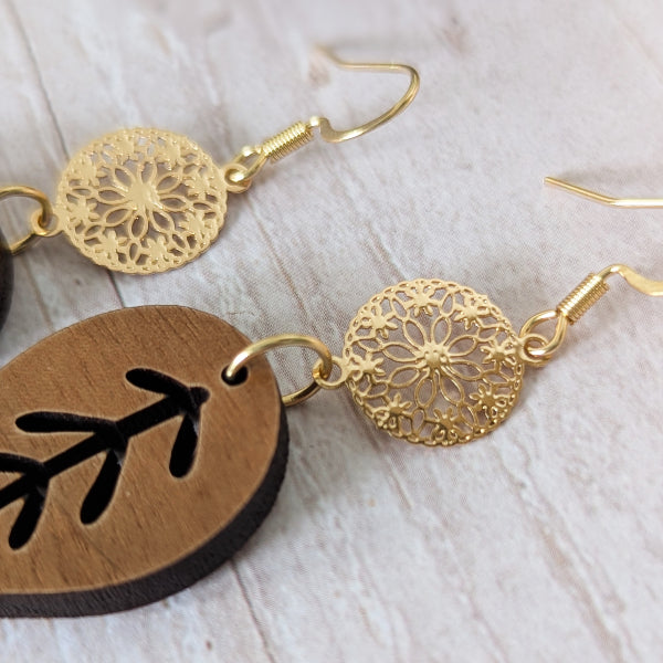 Gold and wooden earrings on a light fabric background