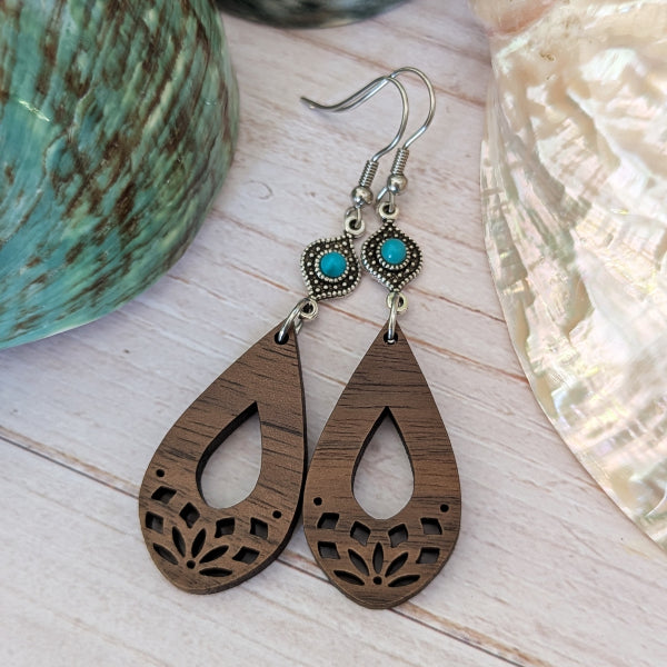 Wooden teardrop earrings with turquoise stones on a light wooden surface. Stainless steel hooks.