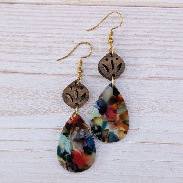 Colorful teardrop earrings with gold hooks on a light wooden surface