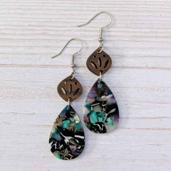 Pair of earrings with floral teardrop design on a light wooden surface