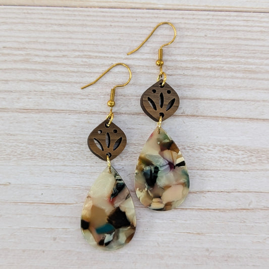 Pair of earrings with teardrop-shaped marbled drops and gold accents on a light wooden surface.