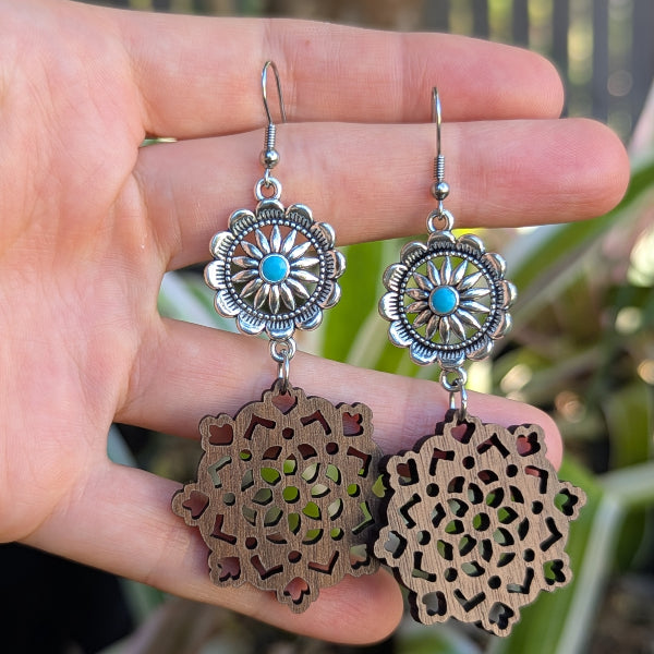 Wooden earrings with silver and turquoise accents held on a hand. Stainless steel hooks.