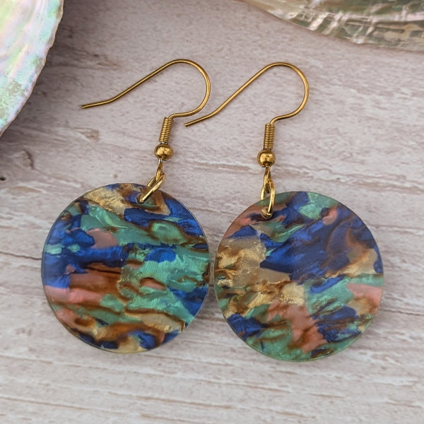 Multicolored round earrings with gold hooks on a wooden surface