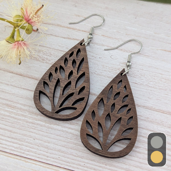 Wooden tear drop earrings on a light wooden surface with flowers in the background. Stainless steel hooks.