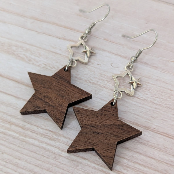 Star-shaped wooden earrings with silver stars on a light wooden surface. Stainless steel hooks.