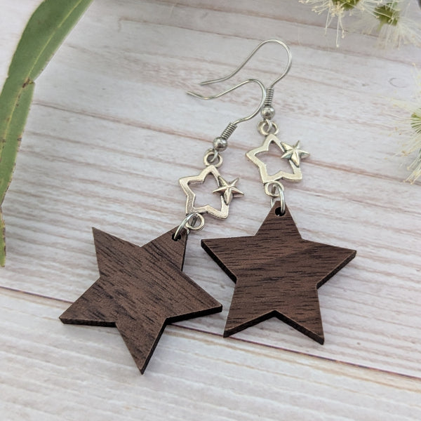 Star-shaped wooden earrings with silver stars on a light wooden surface. Stainless steel hooks.