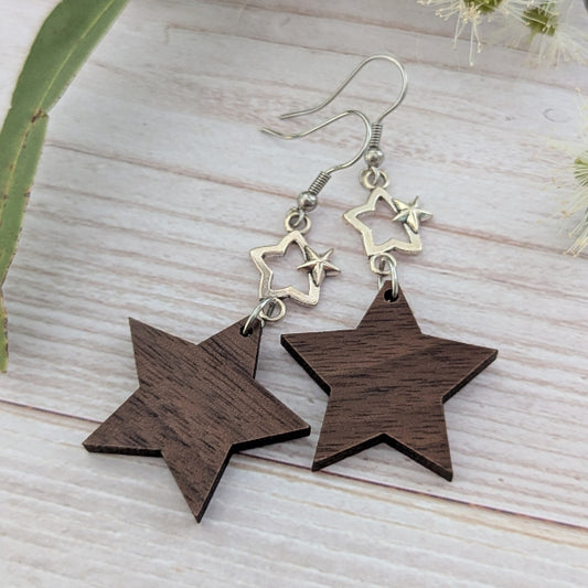 Star-shaped wooden earrings with silver stars on a light wooden surface. Stainless steel hooks.
