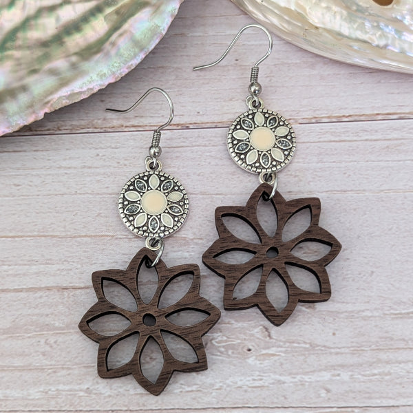 Wooden flower-shaped earrings with silver accents on a wooden surface
