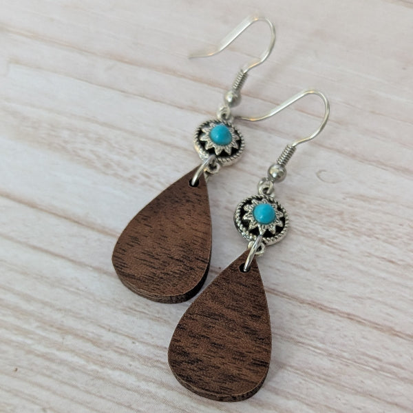 Wooden teardrop earrings with turquoise stones and silver accents on a light wooden surface. Stainless steel hooks.