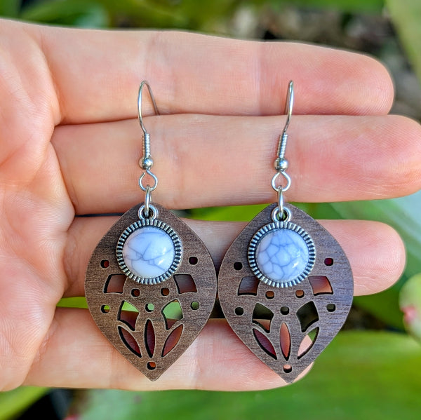 Pair of decorative earrings held in a hand with a natural background