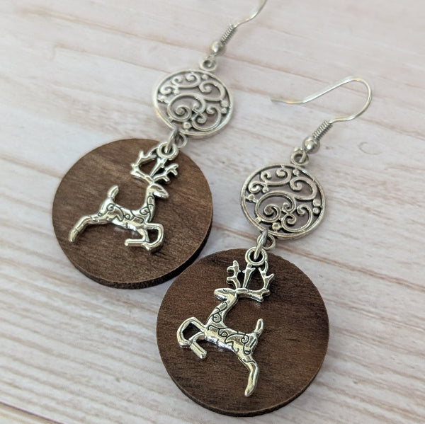 Wooden earrings with reindeer charms on a light wooden surface. Stainless steel hooks.