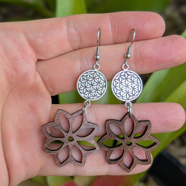 Silver and wooden floral earrings held in a hand with a natural background. Stainless steel hooks.