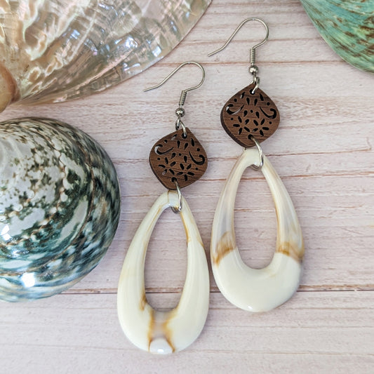 Cream teardrop earrings with wooden floral designs on a wooden surface. Stainless steel hooks.