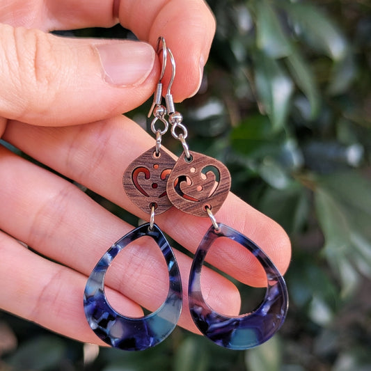 Wooden and blue resin earrings held in a hand.