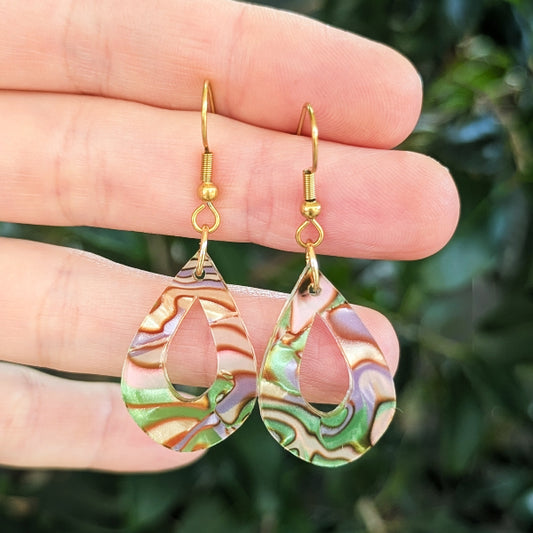 Multi coloured acrylic tear drops with gold toned hooks, against a green blurred background.