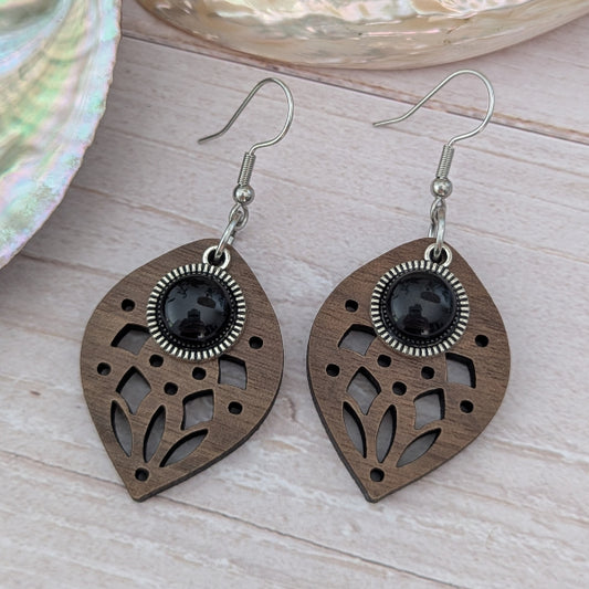 Wooden earrings with black stone centres on a wooden surface. Stainless steel hooks.
