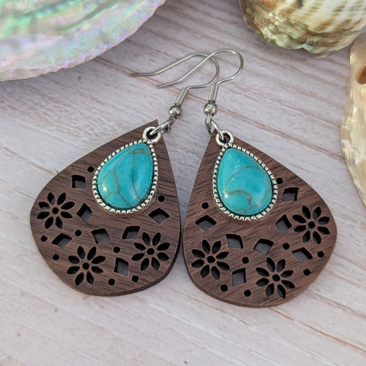 Wooden earrings with turquoise stones on a light wooden surface. Stainless steel hooks.