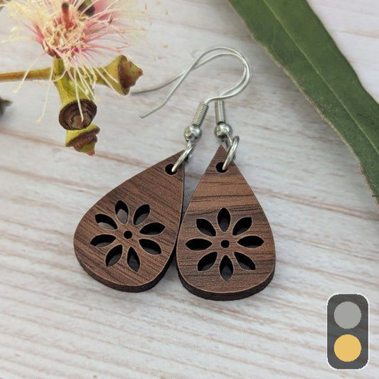 Wooden teardrop earrings with floral cutout design on a light wooden surface. Stainless steel hooks.