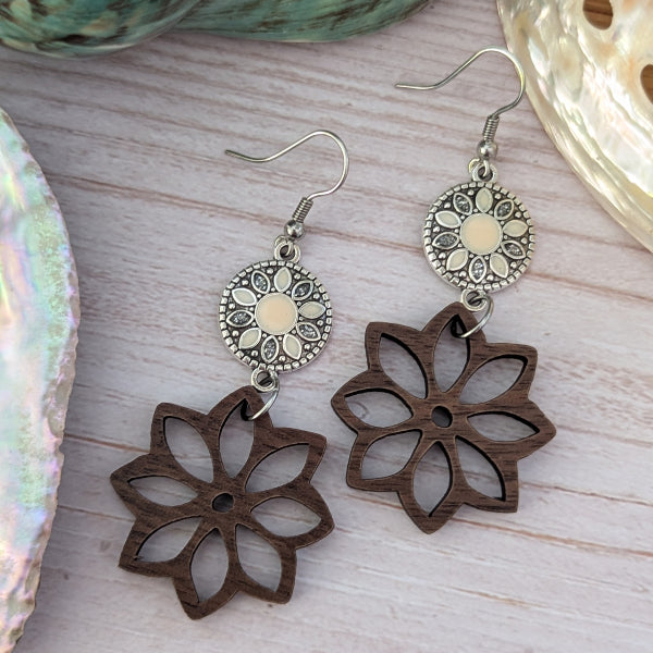 Wooden flower-shaped earrings with silver hooks on a wooden surface.