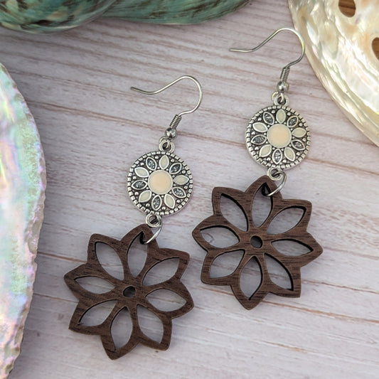 Wooden flower-shaped earrings with silver hooks on a wooden surface.