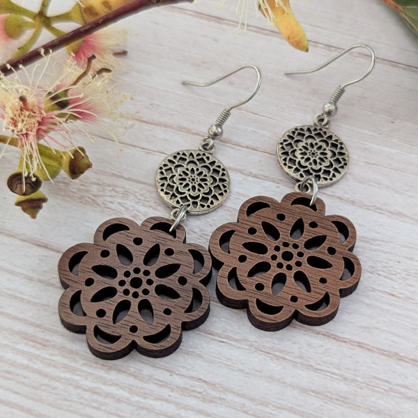 Wooden floral earrings with silver accents on a light wooden surface. Stainless steel hooks.