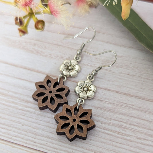 Wooden floral earrings with silver accents on a light wooden surface. Stainless steel hooks.