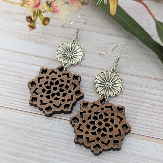 Pair of wooden earrings with floral designs on a light wooden surface. Stainless steel hooks.