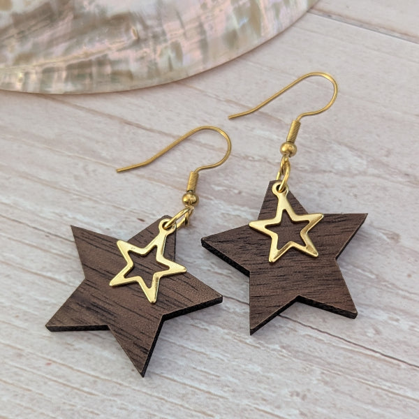 Star-shaped earrings with gold and wooden design on a light wooden surface