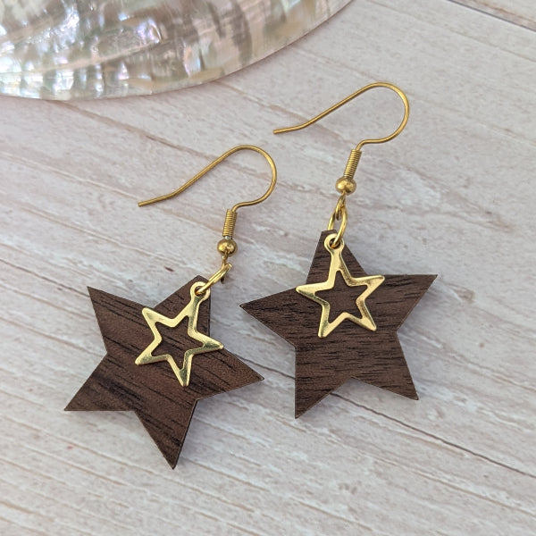 Star-shaped earrings with gold and wooden design on a light wood surface