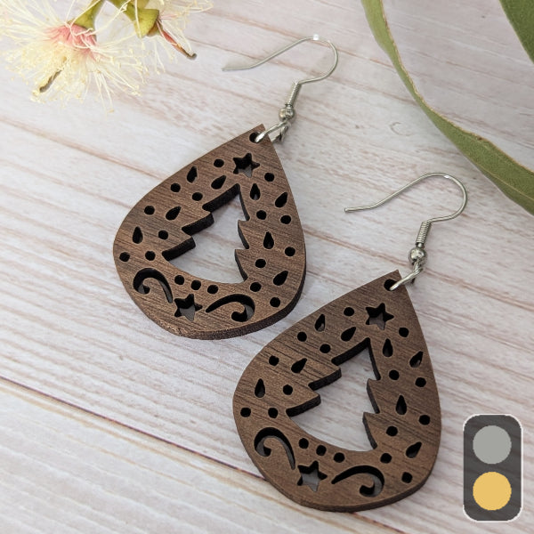 Wooden Christmas earrings with intricate cut-out designs on a light wooden surface. Stainless steel hooks.