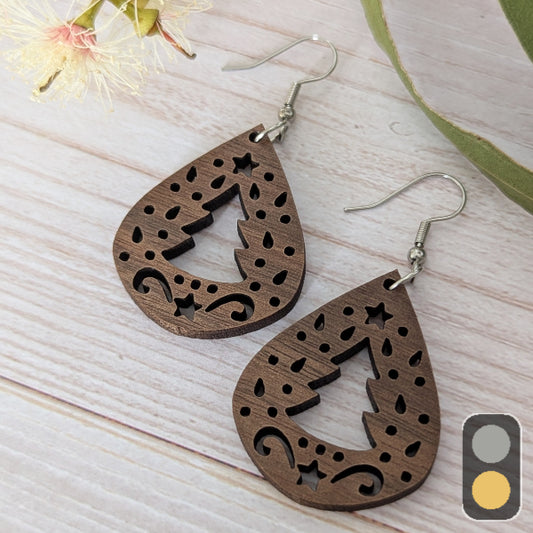 Wooden Christmas earrings with intricate cut-out designs on a light wooden surface. Stainless steel hooks.