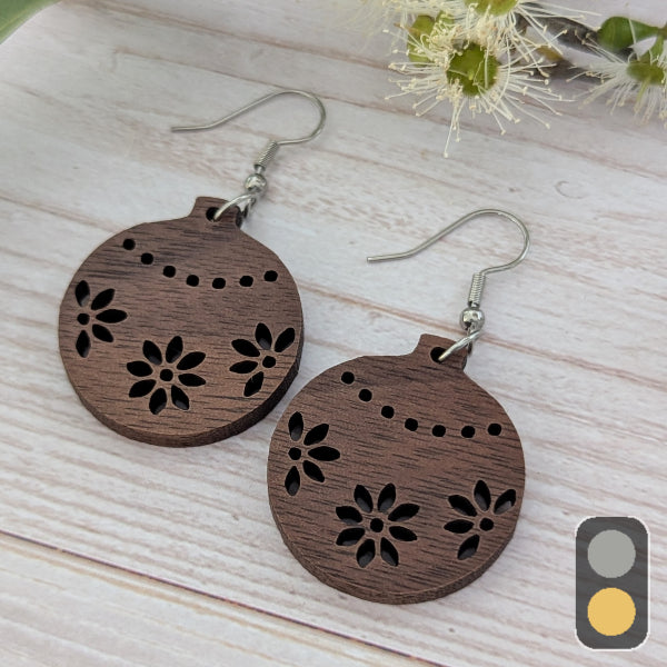 Wooden Christmas bauble earrings with floral cutouts on a light wooden surface. Stainless steel hooks.