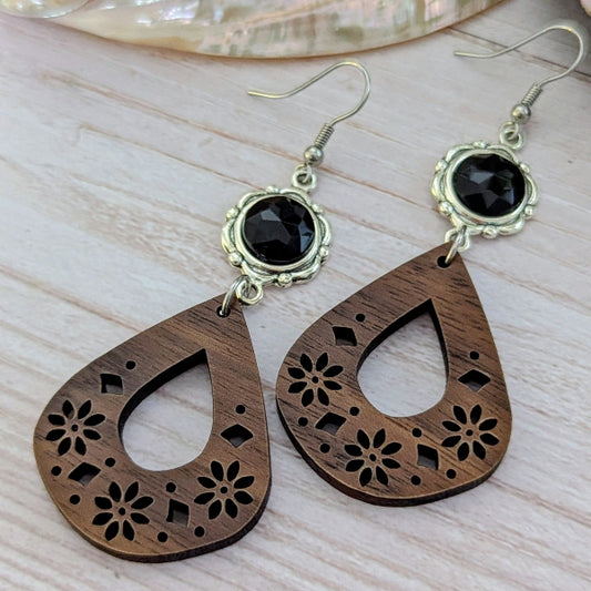 Wooden teardrop earrings with black stones on a light wooden surface