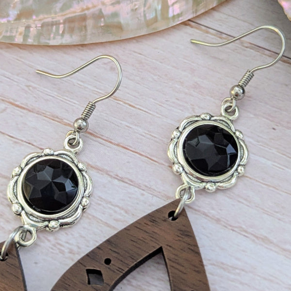 wooden silver earrings with black stones on a wooden surface