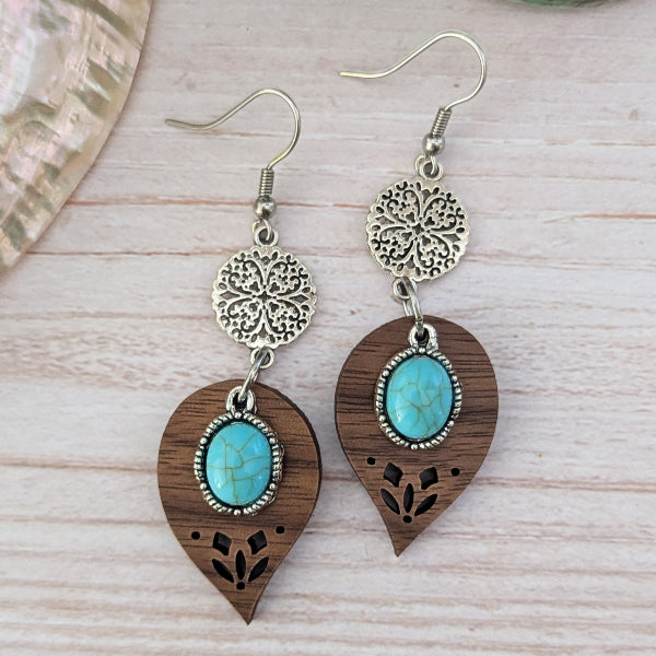 Pair of earrings with wooden and turquoise stone design on a light wood surface