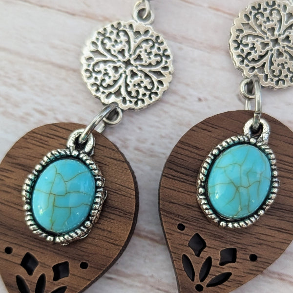 Turquoise stone earrings with silver and wooden accents on a wooden stand.